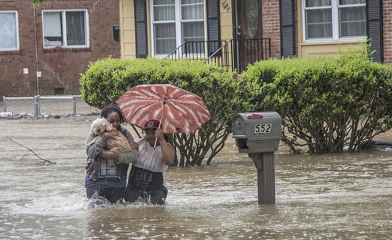 Nautica Jackson, left, and Aniya Ruffin walk through floodwaters with their dog as water threatened to enter their home Tuesday in Raleigh, North Carolina. The National Weather Service had flood watches and warnings in effect in the eastern half of the state Tuesday morning after storms dumped several inches of rain in the Raleigh area.