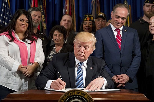 President Donald Trump, accompanied by Veterans Affairs Secretary David Shulkin, center right, and veterans, signs an Executive Order on "Improving Accountability and Whistleblower Protection" at the Department of Veterans Affairs, Thursday, April 27, 2017, in Washington.