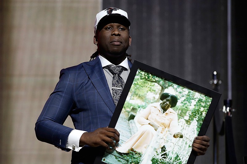 UCLA's Takkarist McKinley carries a photograph of his grandmother onstage after being selected by the Atlanta Falcons during the first round of the 2017 NFL football draft, Thursday, April 27, 2017, in Philadelphia. 