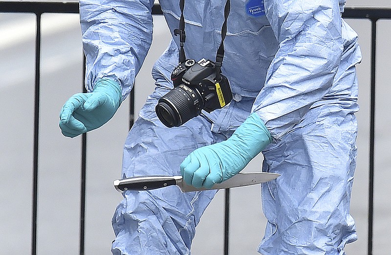 A police forensic Officer holds a knife Thursday at the scene after a man was arrested following an incident at Whitehall in London. London police arrested a man for possession of weapons Thursday near Britain's Houses of Parliament.