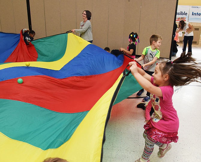 Ava Owens, at right, plays with a parachute during festivities Thursday for Week of the Young Child at Southwest Early Childhood Center (SECC). 
