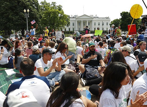Demonstrators sit on the ground along Pennsylvania Ave. in front of the White House in Washington, Saturday, April 29, 2017, during a demonstration and march. Thousands of people gathered across the country to march in protest of President Donald Trump's environmental policies, which have included rolling back restrictions on mining, oil drilling and greenhouse gas emissions at coal-fired power plants. The demonstrators sat down for 100 seconds to mark President Trump's first 100 days in office. 