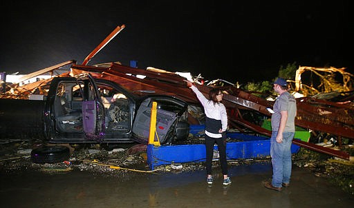 Ernestine Cook of Canton, Texas, points out the damage to spotter Michael Search of Henderson, Texas, as they inspect the damage done to the I-20 Dodge dealership after a tornado hit Canton, Texas, Saturday, April 29, 2017. Cars and trucks were piled high and the service area was destroyed. (Tom Fox/The Dallas Morning News via AP)