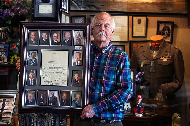 In this April 17, 2017, photo, Eric Corbyn, owner of Corbyn's Clothiers, displays a document bearing the signature of 13 U.S. presidents in Amariloo, Texas. This summer Corbyn hopes to add Trump to the list to make it 14. His late father, a major in the Korean War, collected autographs and photographs. Replicas of the collection hang in the Amarillo store alongside his father's military uniform. 