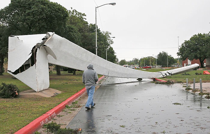 A man walks by the toppled iconic structural arch that welcomed visitors to the annual Oklahoma State Fair in Oklahoma City. Severe thunderstorms have toppled tree limbs and power lines and caused minor flooding across Oklahoma.
