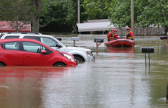 Members of the High Ridge fire department take a boat in at the Village Green Estates trailer park Monday in Cedar Hill. Torrential rains over the weekend caused flash flooding across Missouri, and as storm drains and fields continue to pour into rivers, they continue to rise.