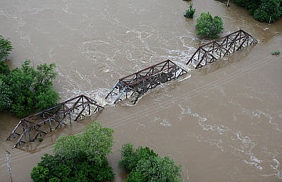 In this Tuesday, May 2, 2017 photo, flood water from the Meramec River streams over a railroad bridge in Valley Park, Mo. River levels are cresting in several Missouri communities as floodwaters slowly drain from the state, although forecasts for more rain could cause another round of damaging high water.