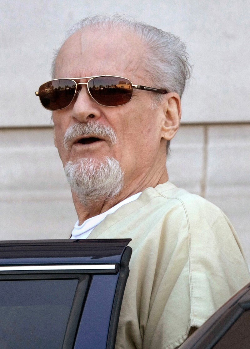 Tony Alamo talks to reporters as he is escorted to a waiting police car on July 23, 2009, outside the federal courthouse in Texarkana, Ark. Alamo, a one-time street preacher whose apocalyptic ministry grew into a multimillion-dollar network of businesses and property before he was convicted in Arkansas of sexually abusing girls he considered his wives, died Tuesday in prison. He was 82. 