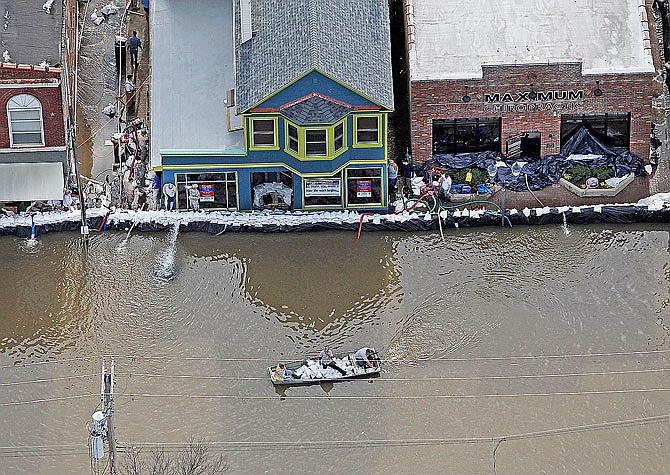 A boat carrying sandbags moves down South Central Avenue on Tuesday in Eureka. River levels are cresting in several Missouri communities as floodwaters slowly drain from the state, although forecasts for more rain could cause another round of damaging high water. 