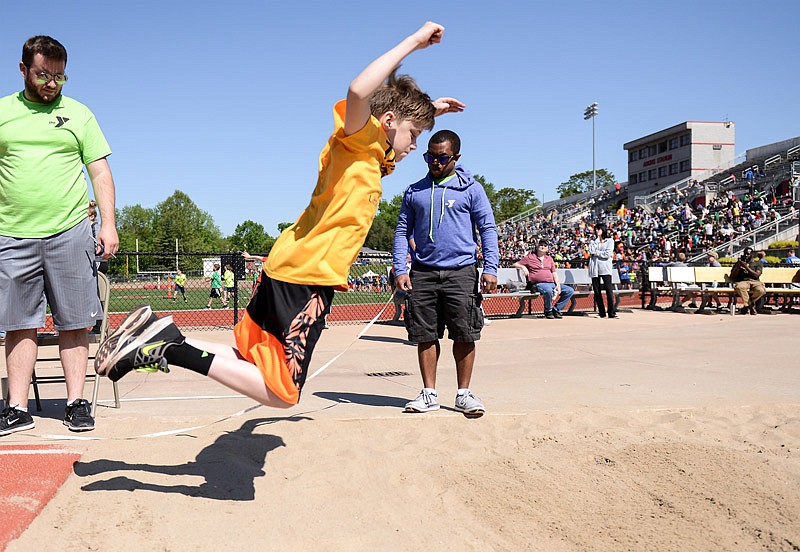 Volunteers hold a measuring tape as fifth grader Jaxson Jobe stretches out in the air before planting his feet in the sand during the boys broad jump Saturday, May 6, 2017 during the annual YMCA Little Olympics at Adkins Stadium.