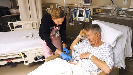 In this Jan. 19, 2017, handout photo from the University of Maryland Shock Trauma Center, nurse Amanda Fritsch checks the catheter delivering a drug that kept Stuart Anders' injured leg numb for three days. Called a nerve block, the non-addictive numbing treatment substantially cut the amount of opioid painkillers that Anders otherwise would have been prescribed for his shattered femur. 