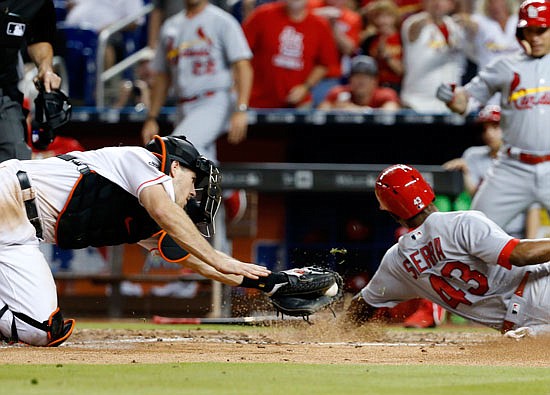 Magneuris Sierra of the Cardinals slides past the tag attempt of Marlins catcher J.T. Realmuto during the ninth inning of Tuesday night's game in Miami.