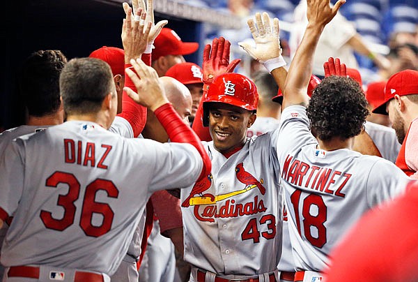 Magneuris Sierra is congratulated by Cardinals teammates after scoring on a triple by Dexter Fowler during the sixth inning of Wednesday night's game against the Marlins in Miami.