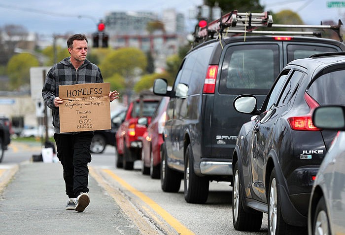 Derek Cote, a homeless man, panhandles in the median strip on a street in Portland, Maine. The city recently began a program to offer day jobs cleaning up parks and other light labor jobs to panhandlers for $10.68 an hour.