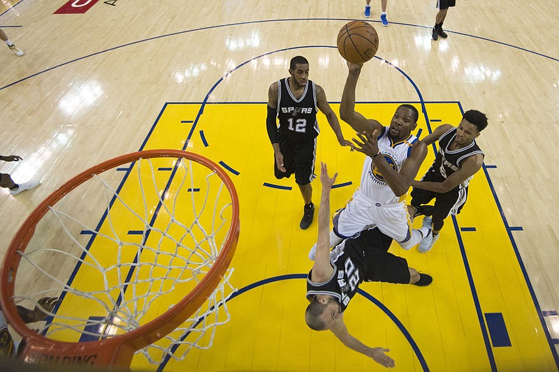 Golden State Warriors forward Kevin Durant, center, shoots between San Antonio Spurs forward LaMarcus Aldridge (12), guard Manu Ginobili (20) and guard Dejounte Murray (5) during the second half of Game 1 of the NBA basketball Western Conference finals in Oakland, Calif., Sunday, May 14, 2017. The Warriors won 113-111. 