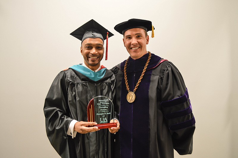 Christopher Smith, left, accepts the University of Arkansas at Hope-Texarkana Alumnus of the Year award from Chancellor Chris Thomason during the recent spring 2017 commencement ceremony.