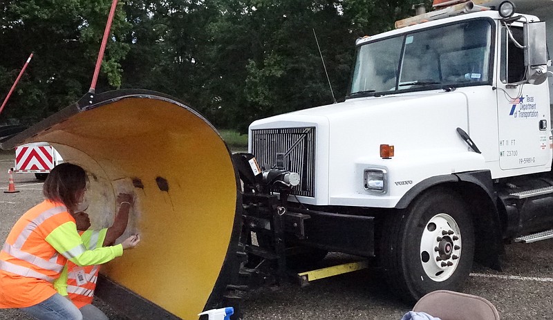 District 19 doesn't often need a snow plow, but it's available for other uses. Kimberly Garner, assistant area engineer from Texarkana, left, and Irene Webster, traffic safety officer of Atlanta, prepare the blade for pictures with children.