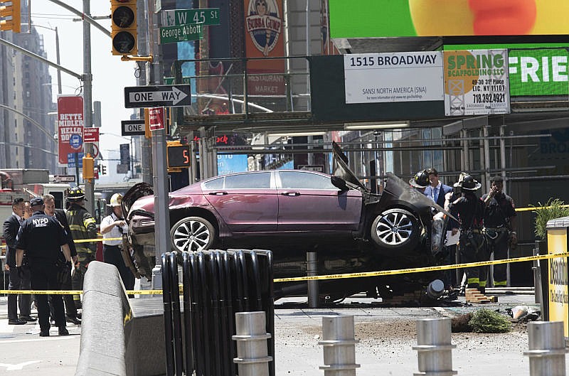 A car rests on a security barrier in New York's Times Square after driving through a crowd of pedestrians, injuring at least a dozen people, Thursday, May 18, 2017.