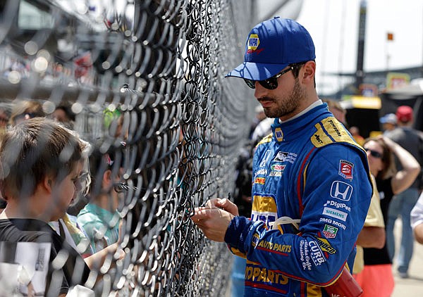 Alexander Rossi signs autographs through the fence in the pit area during Wednesday's practice session for the Indy 500 at Indianapolis Motor Speedway in Indianapolis.