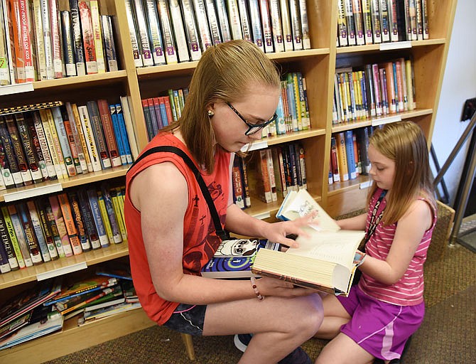 Ruby Ballard, 14, left, and her sister, Lilyona, 9, peruse books on the Missouri River Regional Library Bookmobile in 2017 at its Capital Mall stop near Pizza Hut. The Ballards are regular visitors to the bookmobile and enjoy the opportunity to pick out books and visit with driver Mark Wegman. 