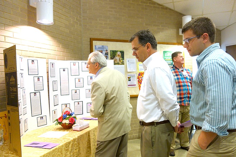 Fulton State Hospital employees Russel DeTempe, left, Robert Sexe and Andrew White look over a collage of former FSH staff members who died in the last year.