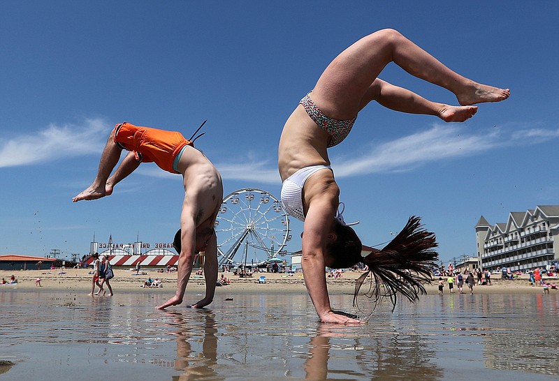 Dan Copeland, left, and Alex Morneau of Biddeford, Maine, former high school cheerleaders, perform back flips while enjoying the record breaking heat, Thursday, May 18, 2017, at Old Orchard Beach, Maine. The temperature climbed well into the 90s in many locations throughout the state. 