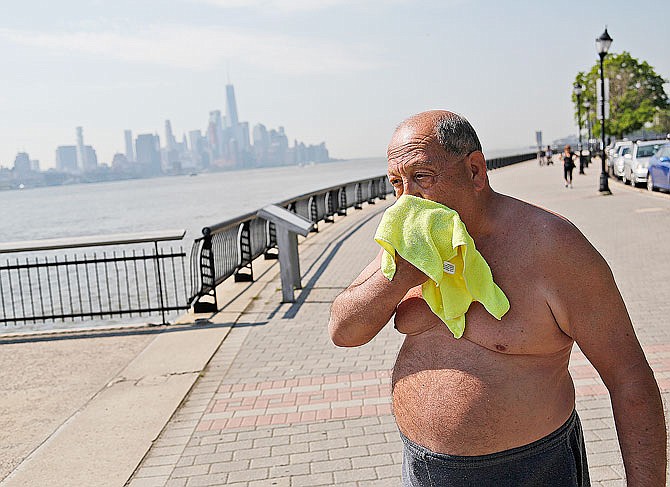 Ed Tirone takes a break from reading on the pier Thursday to wipe a wet washcloth over his face in Hoboken, New Jersey. Forecasters said temperatures across the state could reach above 90 degrees through today. 