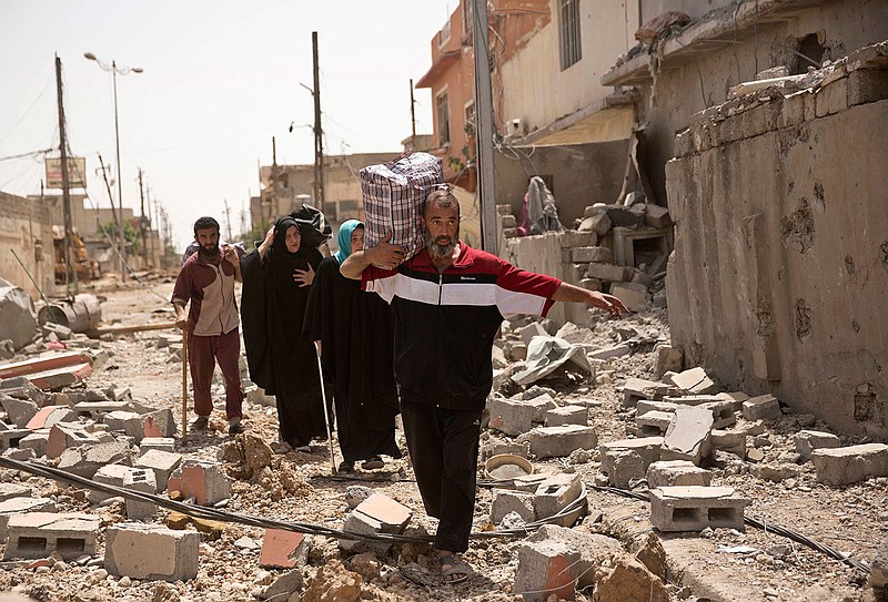 In this May 15, 2017, photo, Iraqi civilians walk through rubble as they flee fighting between Iraqi special forces and Islamic State militants, in western Mosul, Iraq. The United States is looking ahead toward a decisive battleground in its bid to destroy the Islamic State group, even as U.S.-backed local forces must still finish the fight for the extremists' two main strongholds in Iraq and Syria.