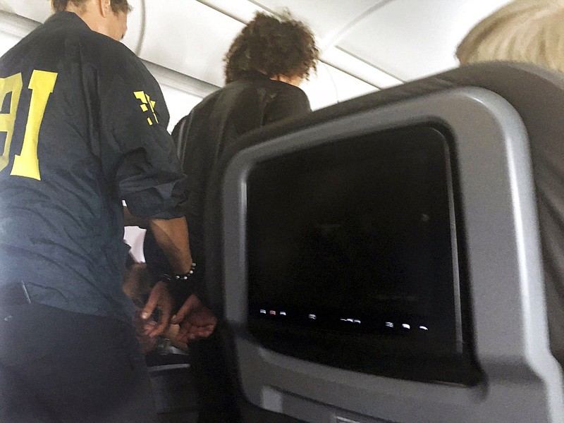 In this photo provided by Donna Basden, a man is escorted off an American Airlines flight after it landed in Honolulu, Friday, May 19, 2017. Federal agents met the plane from Los Angeles when it landed in Honolulu and took the man into custody. 