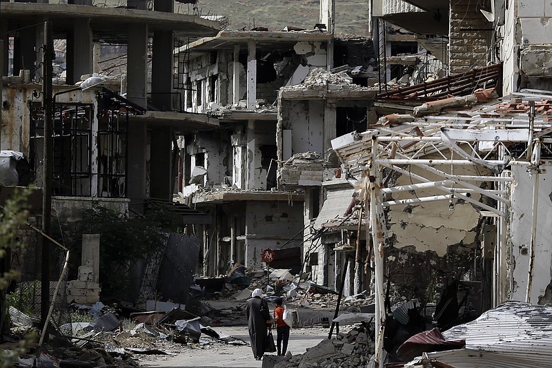 Residents walk through damaged streets at the mountain resort town of Zabadani in the Damascus countryside, Syria, Thursday, May 18, 2017. A U.S. airstrike struck pro-Syrian government forces for the first time, hitting a convoy in the desert near the border with Jordan, U.S. officials and Syrian activists said, an apparent signal to President Bashar Assad to keep his forces out of a zone where U.S.-backed rebels are fighting the Islamic State group. 