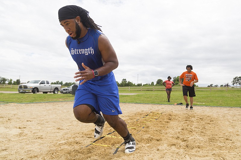 Anthony Rhone, a linebacker at Southern Methodist University, runs agility drills at Bringle Lake on Monday with his sister Alana Rhone and friend Donovan Davis. Rhone is back home from college for the summer and is keeping up on his training while spending time with friends and family.