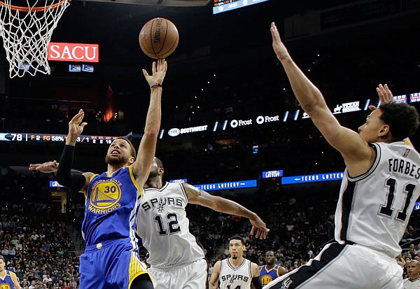 Warriors guard Stephen Curry goes up for a shot as the Spurs' LaMarcus Aldridge (12) and Bryn Forbes (11) defend during the second half in Game 4 of the Western Conference finals Monday in San Antonio.