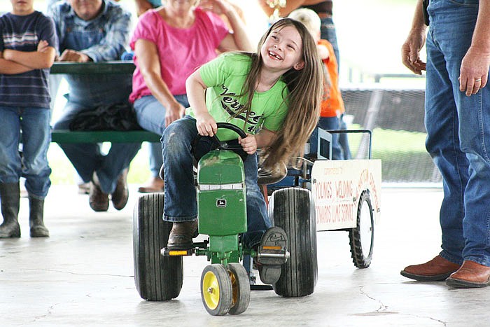 A young girl tries to peddle as far as she can in the pedal tractor pull contest at the 2015 Callaway Youth Expo in Auxvasse.