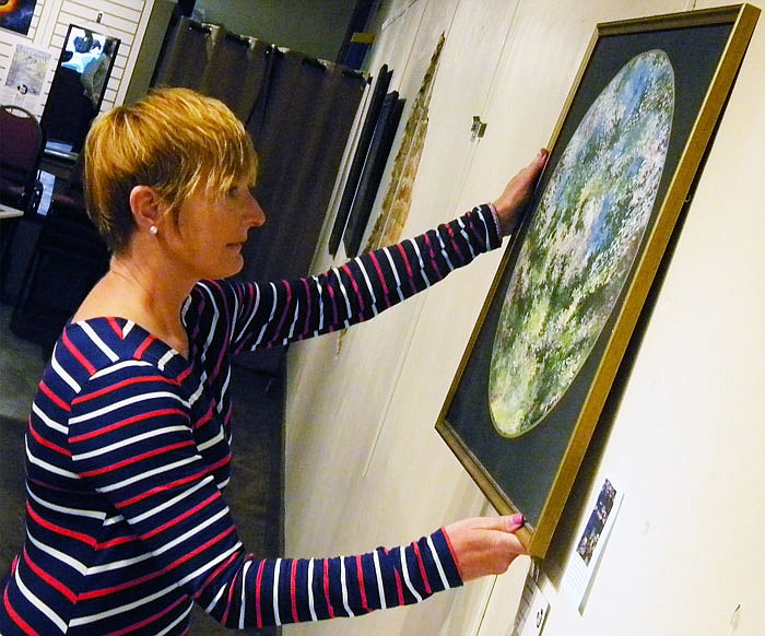 Art House volunteer Lori Bowland removes Pat Kerns' painting "Spring Mandala," making room for the over 150 paintings that will be created during the Callaway Plein Air event.