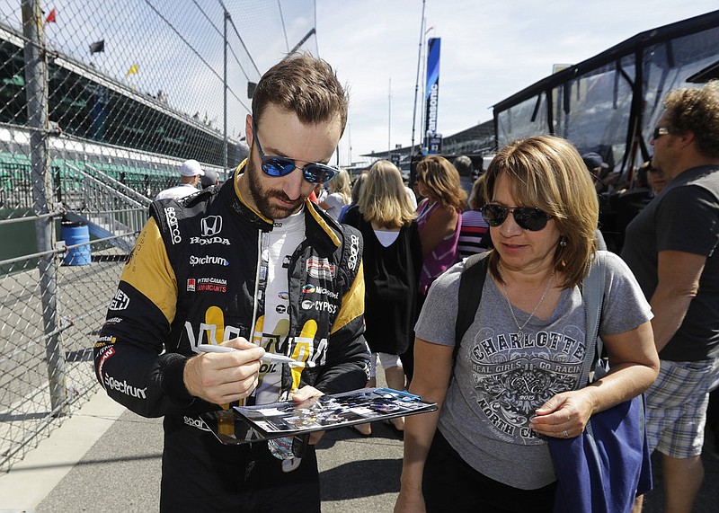 James Hinchcliffe, left, of Canada, gives autographs to fans following a practice for the Indianapolis 500 IndyCar auto race at Indianapolis Motor Speedway, Monday, May 22, 2017, in Indianapolis.