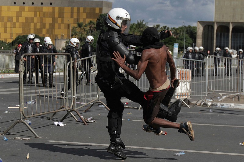 A demonstrator clashes with a police officer during an anti-government protest in Brasilia, Brazil, Wednesday, May 24, 2017. Brazil's president ordered federal troops to restore order in the country's capital following the evacuation of some ministries during clashes between police and protesters who are seeking the leader's ouster.