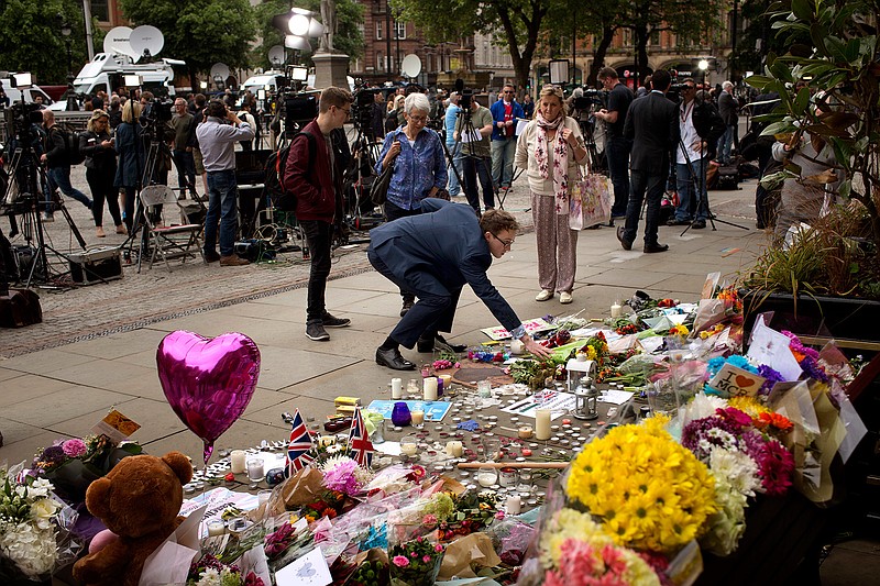 A man places flowers in Albert Square in Manchester, Britain, Wednesday, May 24, 2017, after the suicide attack at an Ariana Grande concert that left more than 20 people dead and many more injured, as it ended on Monday night at the Manchester Arena. 