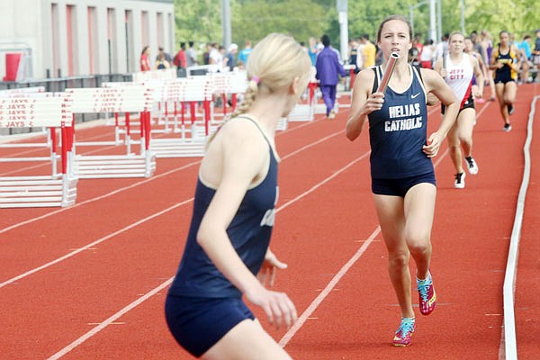 Helias freshman Emma Veltrop (right) prepares to pass the baton in a relay event during a meet earlier this season at Adkins Stadium.