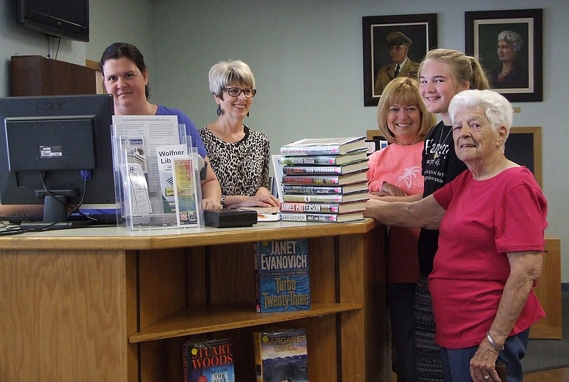 The Wood Place Library has opened its doors again Monday
in almost three months. Some of its first patrons that
day were, from right, Lee McKee, Lanie Holtsclaw, and her
grandmother Debbie Staton. Helping them check out books
are staff members, from left, Erin Ogg, circulation clerk, and
Connie Walker, director. Not pictured is Nancy Lewis, assistant
director.
