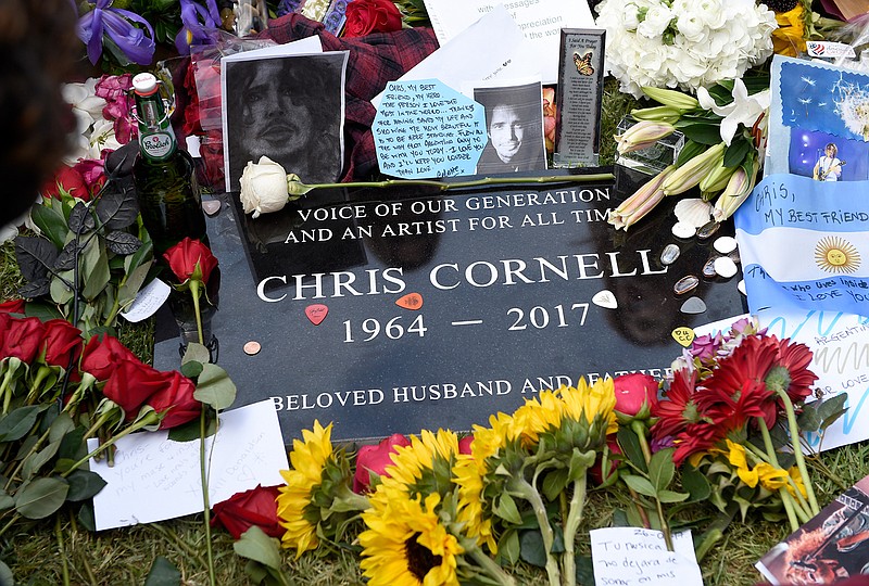 A plaque marking Chris Cornell's gravesite appears, covered in guitar picks, flowers, photos and notes, following the late singer's funeral at the Hollywood Forever Cemetery on Friday, May 26, 2017, in Los Angeles. 