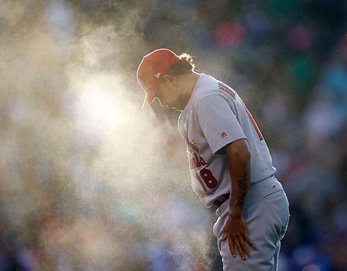 Backlit by the setting sun, Cardinals starting pitcher Carlos Martinez is shrouded by dust after tossing the rosin bag on the mound before facing the Rockies in the fourth inning of Friday night's game in Denver.