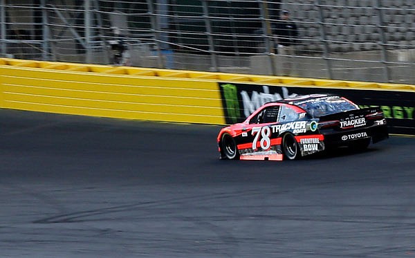 Martin Truex Jr. drives his car into Turn 1 during qualifying Thursday for the NASCAR Cup Series race at Charlotte Motor Speedway in Concord, N.C. There was a sticky substance sprayed on the top section of the turns to help create a second row of racing.