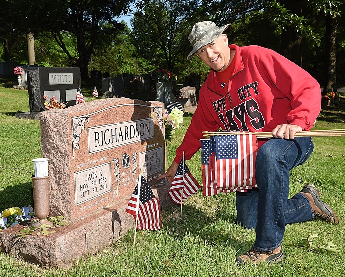 Maj. Charlie Ledgerwood kneels beside the gravestone of a couple who provided military service in the mid-to-late 1940s. Ledgerwood is a member of the MIssouri National Guard and the JCHS National Honor Society sponsor. This marks the second year that members of the NHS visited Riverview Cemetery to place flags at the markers of U.S. military veterans. 