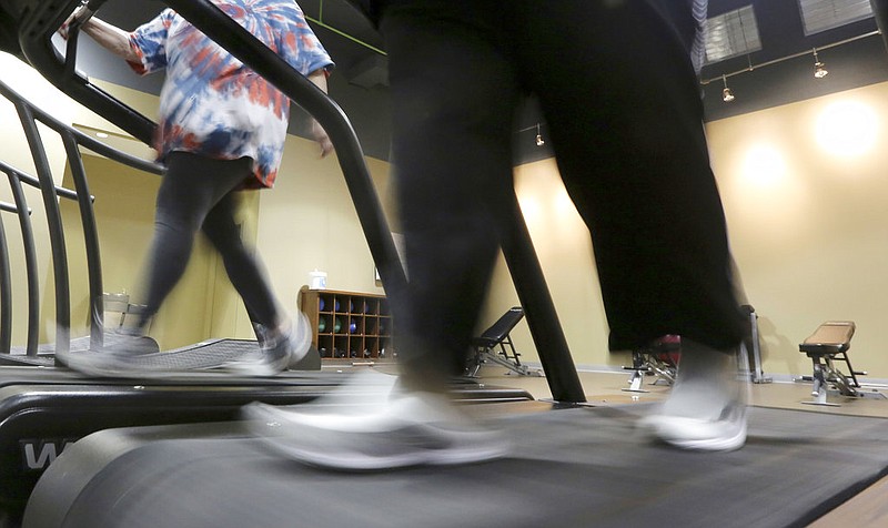 In this Thursday, Jan. 3, 2013 file photo, gym members use a treadmill to warm up for a morning exercise class in Addison, Texas.