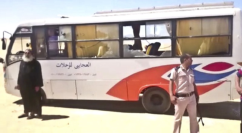This image released by the Minya governorate media office shows a policeman and a priest next to a bus after stormed the bus in Minya, Egypt, Friday, May 26, 2017. Egyptian officials say dozens of people were killed and wounded in an attack by masked militants on a bus carrying Coptic Christians, including children, south of Cairo.