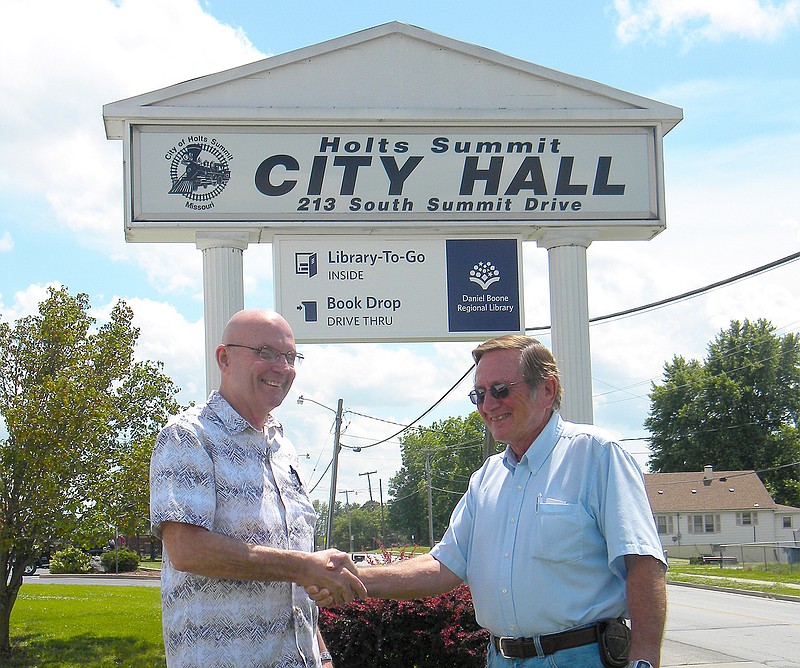 Holts Summit City Administrator Rick Hess, left, shakes hands Wednesday with Jim Frazer, soon-to-be-former president of the Village of Lake Mykee. During the final meeting of the Lake Mykee board of trustees today, final actions will be taken and the Village of Lake Mykee will be consolidated with Holts Summit.