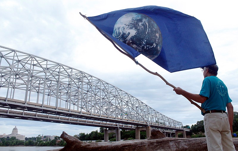 Dick Dalton holds an Earth flag Saturday, June 3, 2017 during the March for Truth event at the Noren River Access in north Jefferson City. Dalton said he often carries the flag around town to advocate peace.