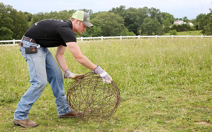 Chance Sommerer rolls "tumbleweeds" out of barbed wire in Jefferson City last week. Sommerer is selling items from burned rolls of barbed wire fence damaged in recent fires in Kansas. The money raised is returned to the farmers to buy new wire for fencing their cattle. 