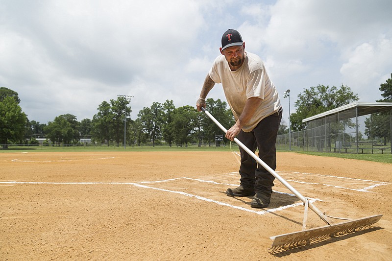 Justin Newton of the Texarkana, Ark., Parks and Recreation Department levels dirt Monday at a softball field at Hobo Jungle Park. The Parks and Recreation Department painted white lines and performed other general maintenance at the fields.