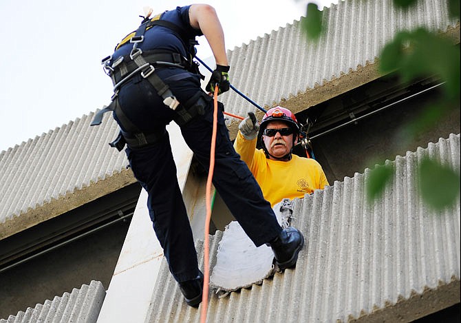 Instructor Ken Vomund, assistant fire chief of O'Fallon, assists a participant in rapelling down the side of the municipal parking garage Thursday during the University of Missouri Summer Fire School.